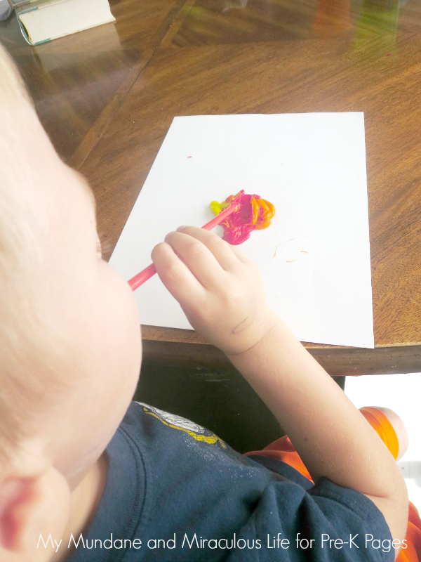 child using straw to paint with